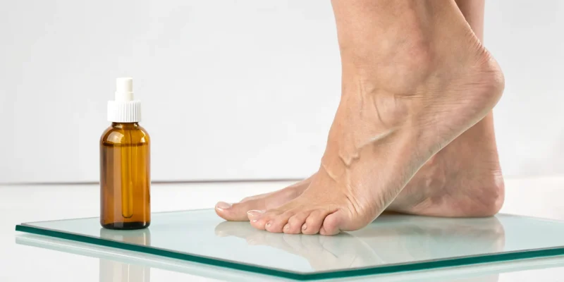 A dropper bottle of the best supplement for nerve pain next to a person's feet.